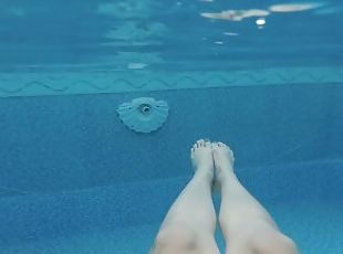 POV of girl's legs swimming in public pool