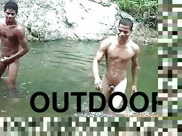 Two brown Latin boys having wet oral fun outdoors