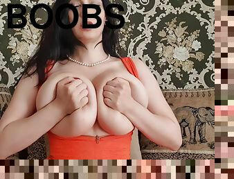 Brunette camslut in orange dress plays with monster boobs on webcam - solo boob play