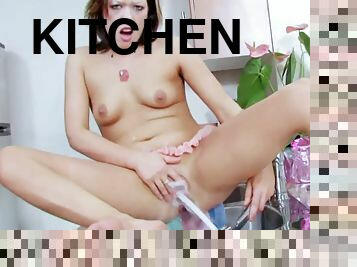 Young solo chick pleases her tight cunt with a water faucet in the kitchen