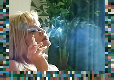 Horny blonde enjoys smoking while posing